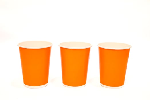 Three vibrant orange paper cups arranged against a clean white background, studio shot photo