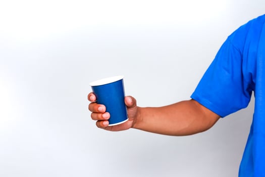 Hand Holding a Blue Paper Cup Against a Plain White Background, simple and clean photo