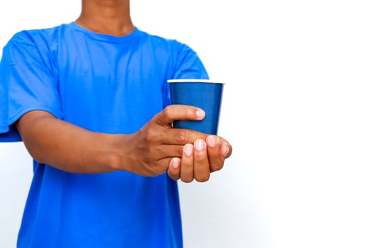 Man in Blue Shirt Offering a Blue Paper Cup Against a Clean White Background photo