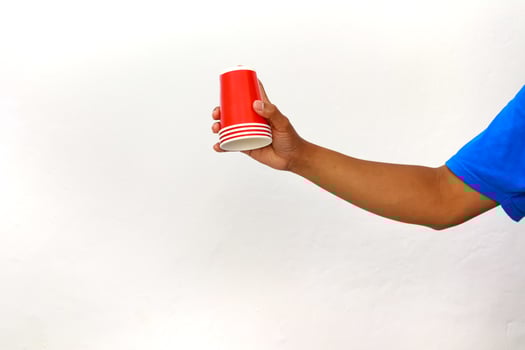 An arm holding a stack of red disposable party cups against a white background photo