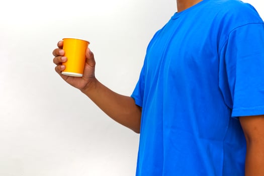 Person in blue shirt holding yellow cup in hand, isolated on white background, studio shot photo