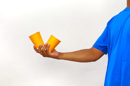 Person Holding Two Orange Cups in Hand Against a White Background Studio Shot photo
