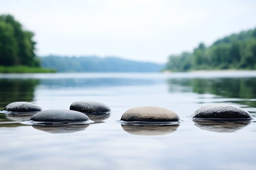 Three stones are sitting in the water next to a river photo