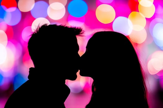 A couple kissing in front of colorful lights photo