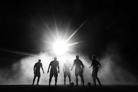 A group of soccer players standing in the dark with a light shining on them photo
