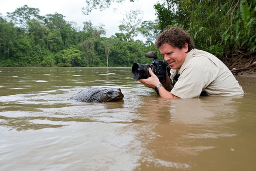 A man taking a photo of a manatee in the water