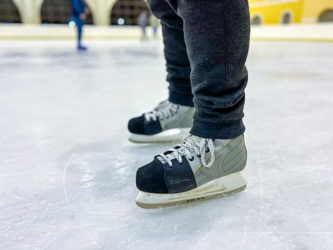 Ice skater wearing modern ice skates on ice rink surface photo