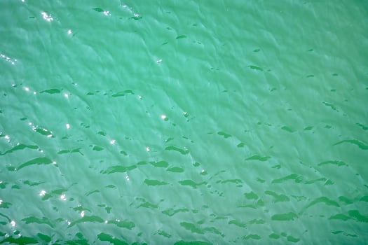 Water surface topview. Sun glare on water. Background abstracted wallpaper texture photo