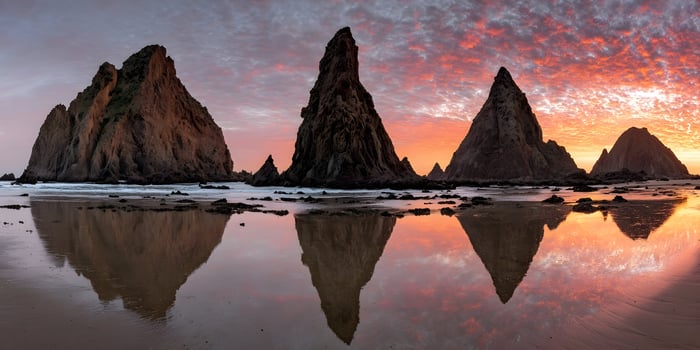 Sunset Beach Scene with Four Rock Formations Reflecting in Calm Water photo