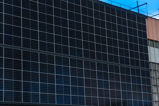 Array of Photovoltaic Cells Covering Exterior Wall for Sustainable Energy Generation with Cloudy Sky and Building Structure photo