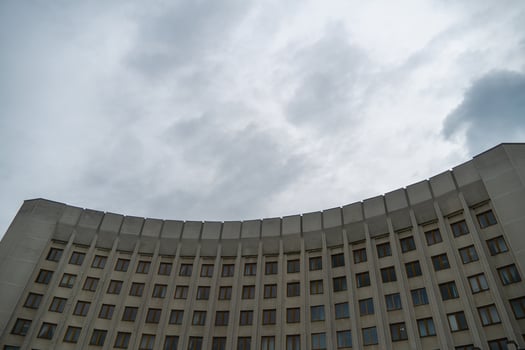 A contemporary structure with numerous windows stands against an overcast sky. The building's curved design highlights modern architectural trends, creating a striking silhouette photo