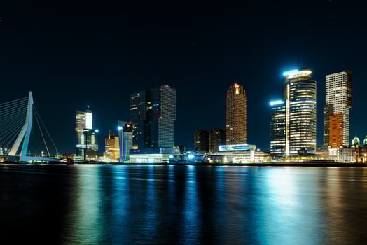 A mesmerizing night panorama of the city of Rotterdam, showcasing its modern high-rise architecture against a backdrop of a starry night sky, creating an enchanting and captivating urban landscape. photo