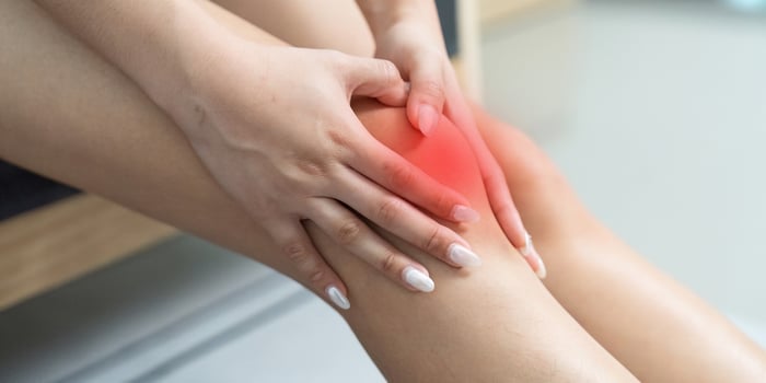 Knee Pain Awareness. Woman applying pressure to her knee in discomfort. photo