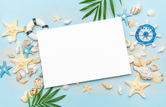 Blank card surrounded by seashells and starfish on sandy beach photo