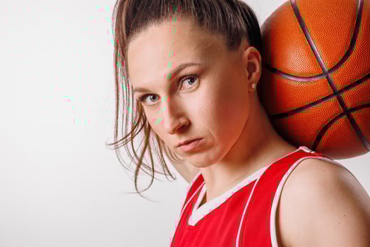 Determined Female Basketball Player in Red Jersey with Ball, Focused Athletic Portrait on White photo