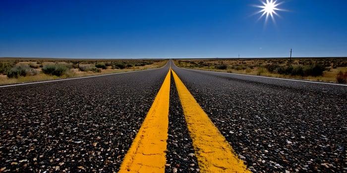 Asphalt Road Cutting Through Desert Under Bright Sun photo
