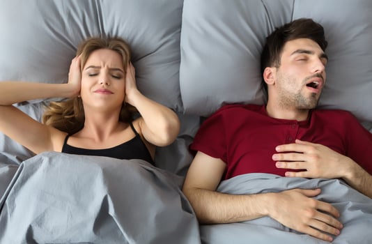 Snoring husband. Angry woman covering ears, top view in bed. photo
