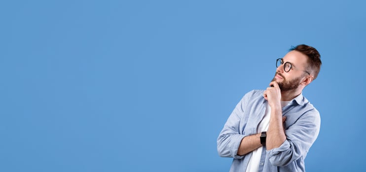 Pensive Caucasian guy thinking over decision or problem, looking at empty space over blue studio background. Thoughtful bearded man hoping, imagining,making choice photo