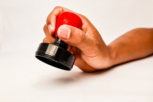 Hand holding a red and black rubber stamp, ready for official approval and paperwork photo