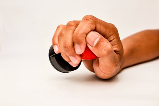 A hand holding a black and red rubber stamp ready to apply to a document or form for approval photo