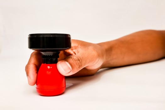 An African American male holding a red and black stamp with a clean background for professional office work photo