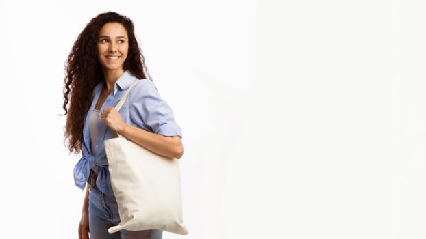 No Plastic. Happy Woman Carrying Flax Eco Bag Posing Looking Aside On White Studio Background. Eco-Friendly Shopping, No Plastic Life, Ecology Concept. Panorama With Copy Space photo