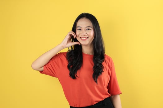 Portrait of Young Asian Indonesian Female making Love Heart Sign on Her Cheek photo