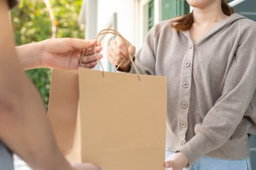 Happy smiling Asian woman receive paper bag parcel of food from courier front house. Delivery man send deliver express. online shopping, paper container, takeaway, postman, delivery service, packages photo