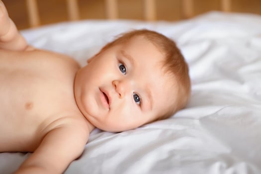 Closeup portrait of cute little baby boy or girl laying in wooden crib, free space. Beautiful toddler looking at camera, lying in baby bed. Babies, little kids, toddlers, infants concept photo