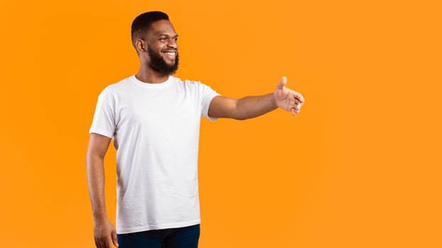 Side View Of Black Man Stretching Hand For Handshake Greeting Aside Standing Posing Over Yellow Studio Background. Nice To Meet You, Shaking Hands Greeting Gesture Concept. Panorama, Free Space photo