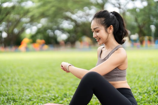 Yoga and Mindfulness. Young woman smiling while practicing yoga stretches outdoors with a laptop. photo