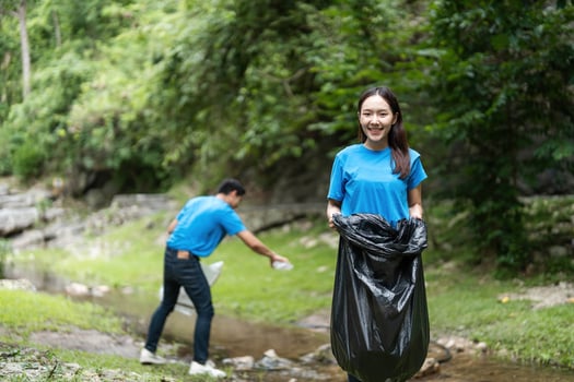 Volunteer teamwork. Young woman and man cleaning up a stream. photo