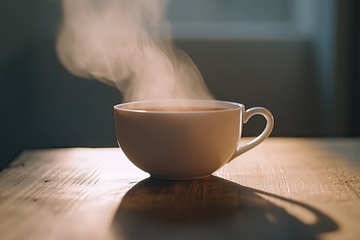 A cup of tea on a table with steam coming out of it photo