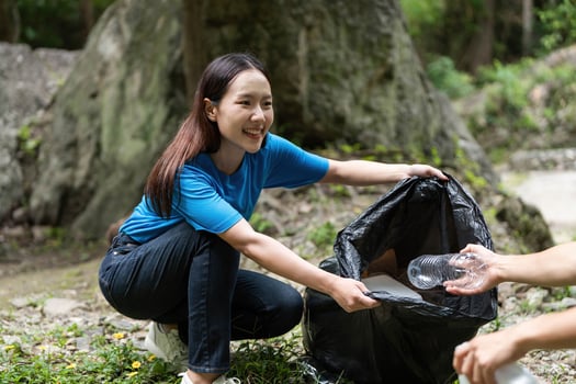 Volunteer Clean-Up Effort. A young woman collecting trash in nature during an environmental initiative. photo