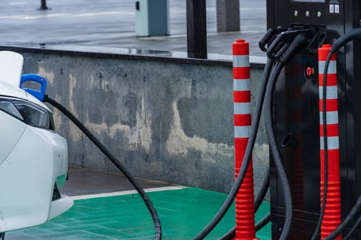 An electric vehicle is being charged at a contemporary station designed for electric cars, with charging cables connecting the car to the station photo