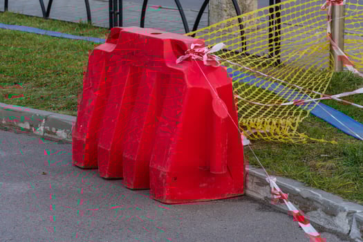 A striking red barrier stands guard on a city street, surrounded by yellow construction netting. Caution tape flutters gently in the breeze, alerting pedestrians to the ongoing work nearby photo