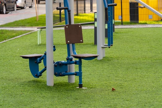 Various gym machines are positioned on artificial grass in a community park, encouraging outdoor fitness activities and a commitment to healthy living photo