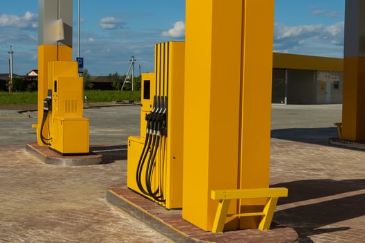 Bright yellow gasoline dispensers stand ready at a modern gas station. The setting is spacious with clear blue skies, showcasing an inviting atmosphere for vehicles needing fuel photo