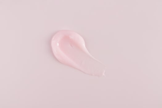 A beautiful sample of a cosmetic texture stroke of lip balm or lip skin care mask. Delicate pink texture. top view. A copy space. pink background photo