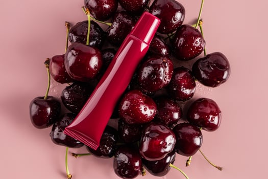 Cosmetic packaging A tube of lip balm rests on ripe juicy cherries. top view. A blank cosmetic packaging mockup. Product presentation. photo