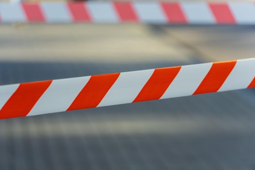 Vibrant orange and white striped barrier tape stretches across the path, signaling a construction zone in a bustling city, urging pedestrians to detour photo