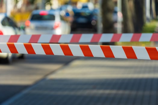 A vivid scene captures a barrier with distinct red and white stripes, preventing entry to a busy street filled with parked cars and blurred city life beyond photo