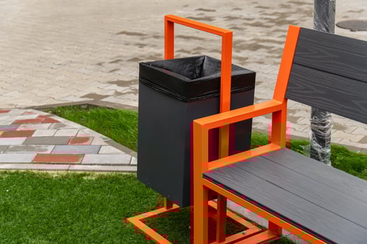 A stylish garbage container is integrated with a bench in a green park area, encouraging visitors to dispose of trash responsibly while enjoying the outdoors photo