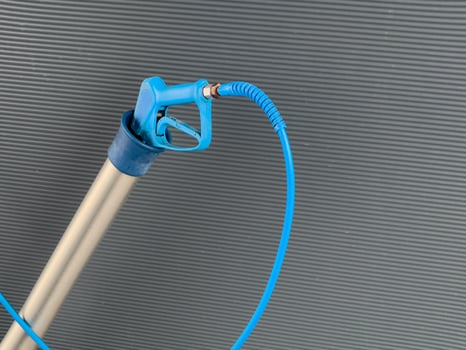 A high-pressure car washer gun is prepared for washing vehicles, featuring an ergonomic grip and a sturdy hose. It is situated at a car wash, ready for action photo