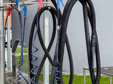 High pressure car washer guns and hoses are organized at a car wash station, prepared for cleaning vehicles effectively under bright daylight photo