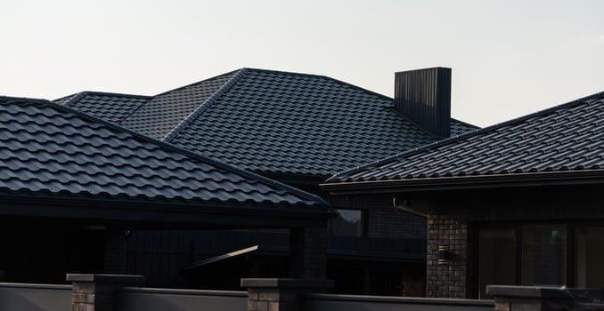 The image captures the unique rooftops of contemporary houses, showcasing distinct textured tiles and architectural features against a clear sky photo