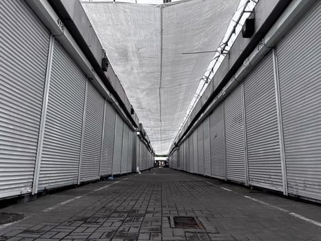The empty market features countless closed stalls, their shutters down, as a soft light filters through the canopy above in the peaceful morning air photo