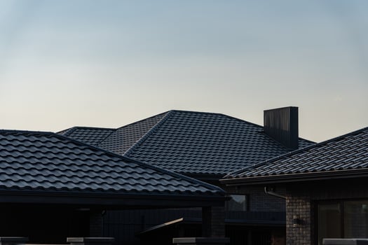 The rooftops of contemporary houses are silhouetted against a serene evening sky, highlighting their sleek design and tiles as the day transitions to night photo