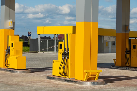 Bright yellow fuel pumps stand at a newly opened gas station with a blue sky overhead. The area is spacious and well-lit, offering a clean and modern look photo