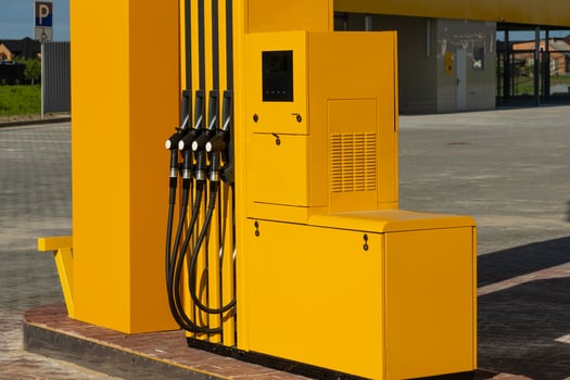 The bright yellow dispenser, featuring multiple hoses, is positioned at a gas station during the day, ready for vehicles to refuel conveniently photo